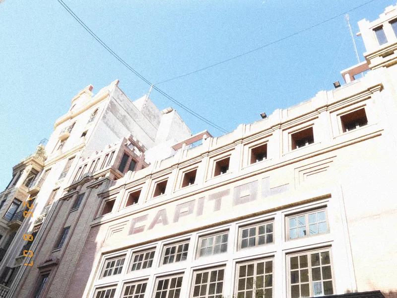A large, white, art-deco style building with the word "capitol" across the front